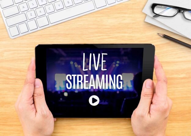 Hand holding tablet with Live Streaming word on wood table ,Inte